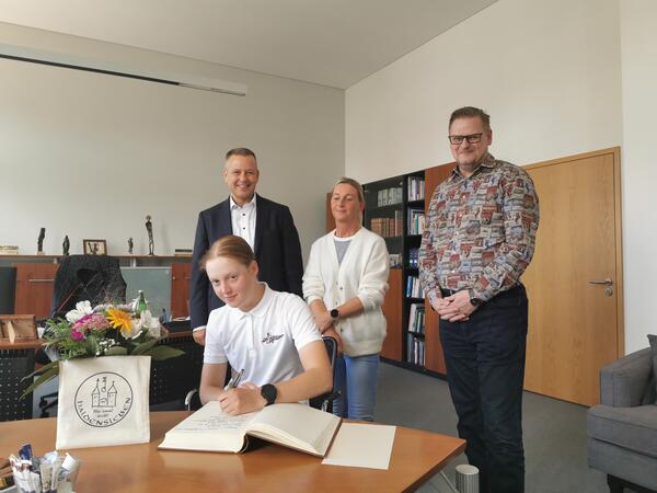 Mara Benecke trägt sich in Ehrenbuch der Stadt ein. Dahinter v.l. Bürgermeister Bernhard Hieber, Maras Mutti Nadine Benecke und Dezernent Oliver Karte.